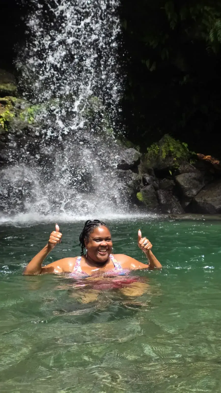 A happy guest swimming below a waterfall